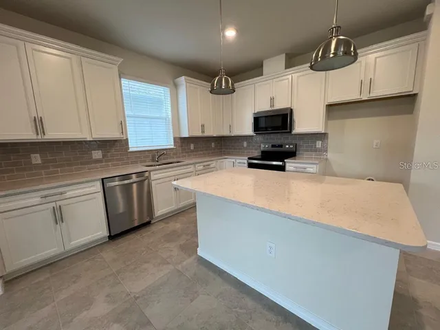 a kitchen with granite countertop a sink a stove and cabinets