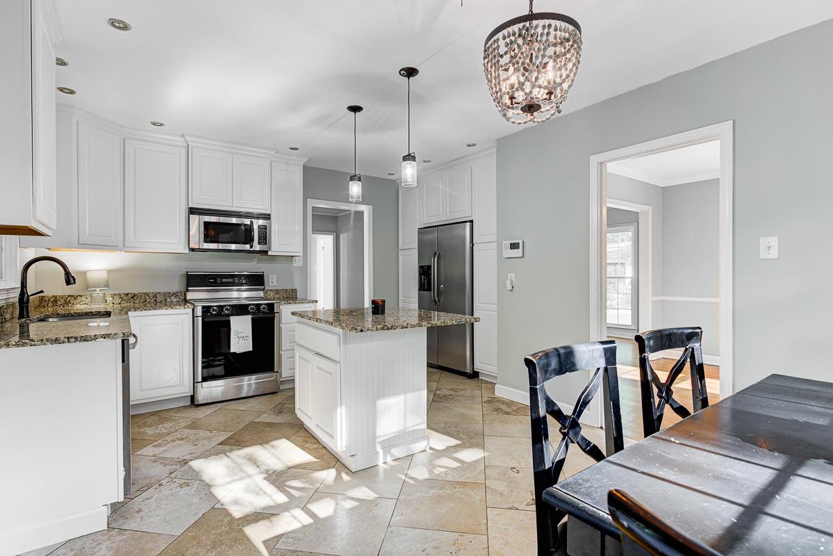 5676 Barfield Road Memphis, TN 38120 - Photo 1 of 19 Kitchen featuring white cabinetry, stainless steel appliances, granite countertops, and a central island