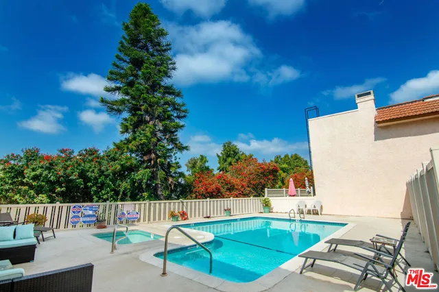 a view of swimming pool with seating area and trees in the background