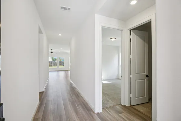 a view of a hallway with wooden floor and a bathroom