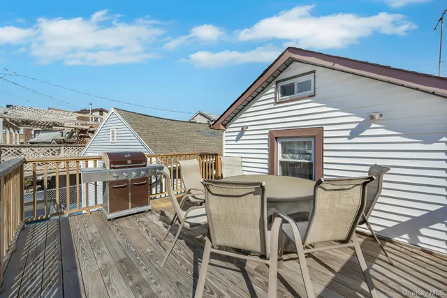 a view of a roof deck with table and chairs with wooden floor and fence