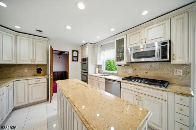 a kitchen with stainless steel appliances granite countertop a refrigerator sink stove microwave and cabinets