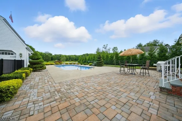 a view of swimming pool with seating space and trees in the background