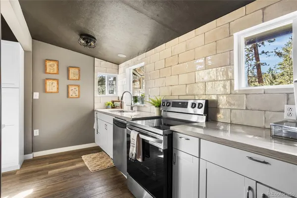 a kitchen with stainless steel appliances granite countertop a sink and a stove next to a window