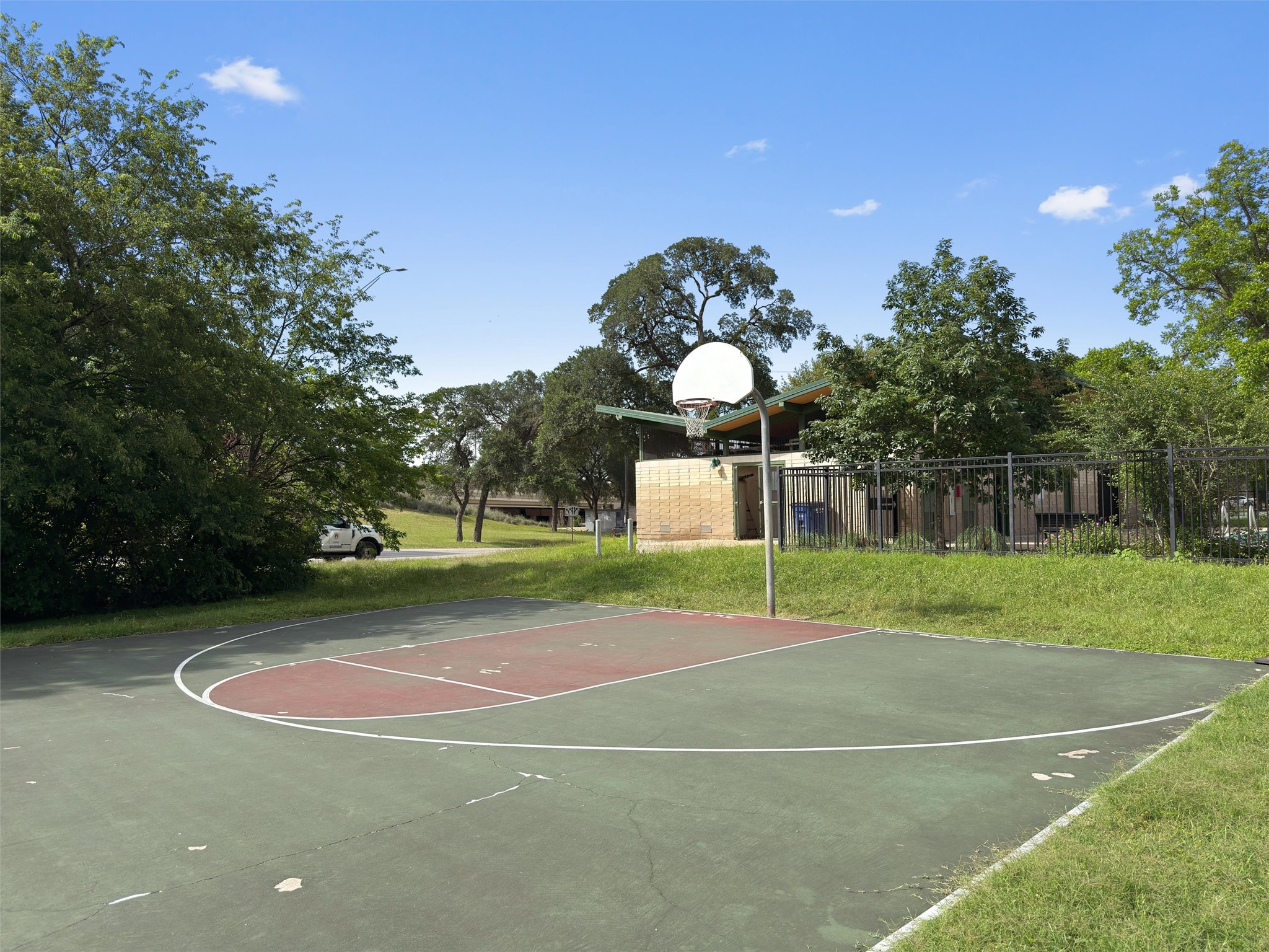 2208 Enfield Road, Unit 10500 Austin, TX 78703 - Photo 31 of 34 Outdoor recreational court featuring a basketball hoop with a clear backboard, green and red painted surface, and white court lines