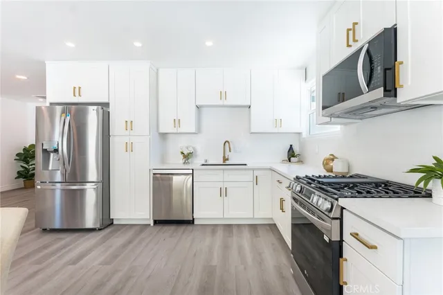 a kitchen with stainless steel appliances granite countertop a sink stove and refrigerator
