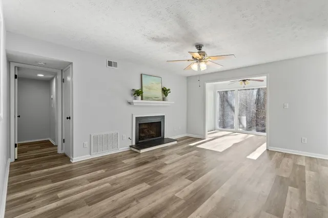 a view of an empty room with chandelier fan and a fireplace