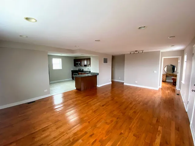 a living room with hard wood floors and a kitchen
