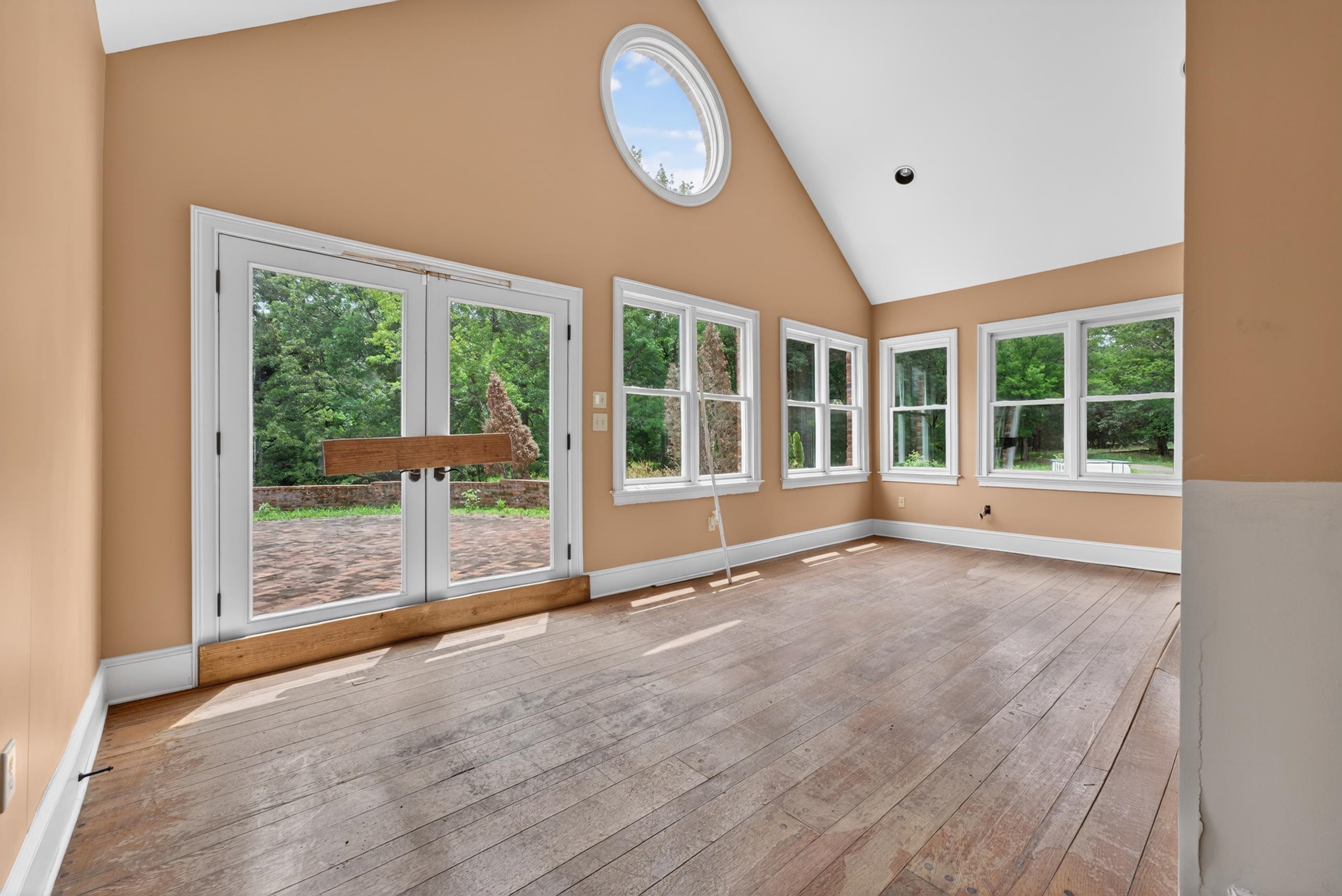 530 West Raines Road Memphis, TN 38109 - Photo 22 of 38 Vaulted ceiling room with multiple white-framed windows, wide plank wood-finish flooring, and white baseboards