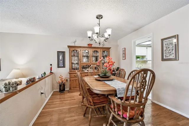 a dining room with wooden floor a chandelier a wooden table and chairs
