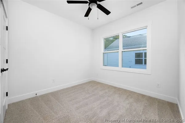 an empty room with a ceiling fan and window