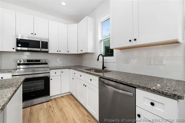 a kitchen with granite countertop white cabinets stainless steel appliances and a sink