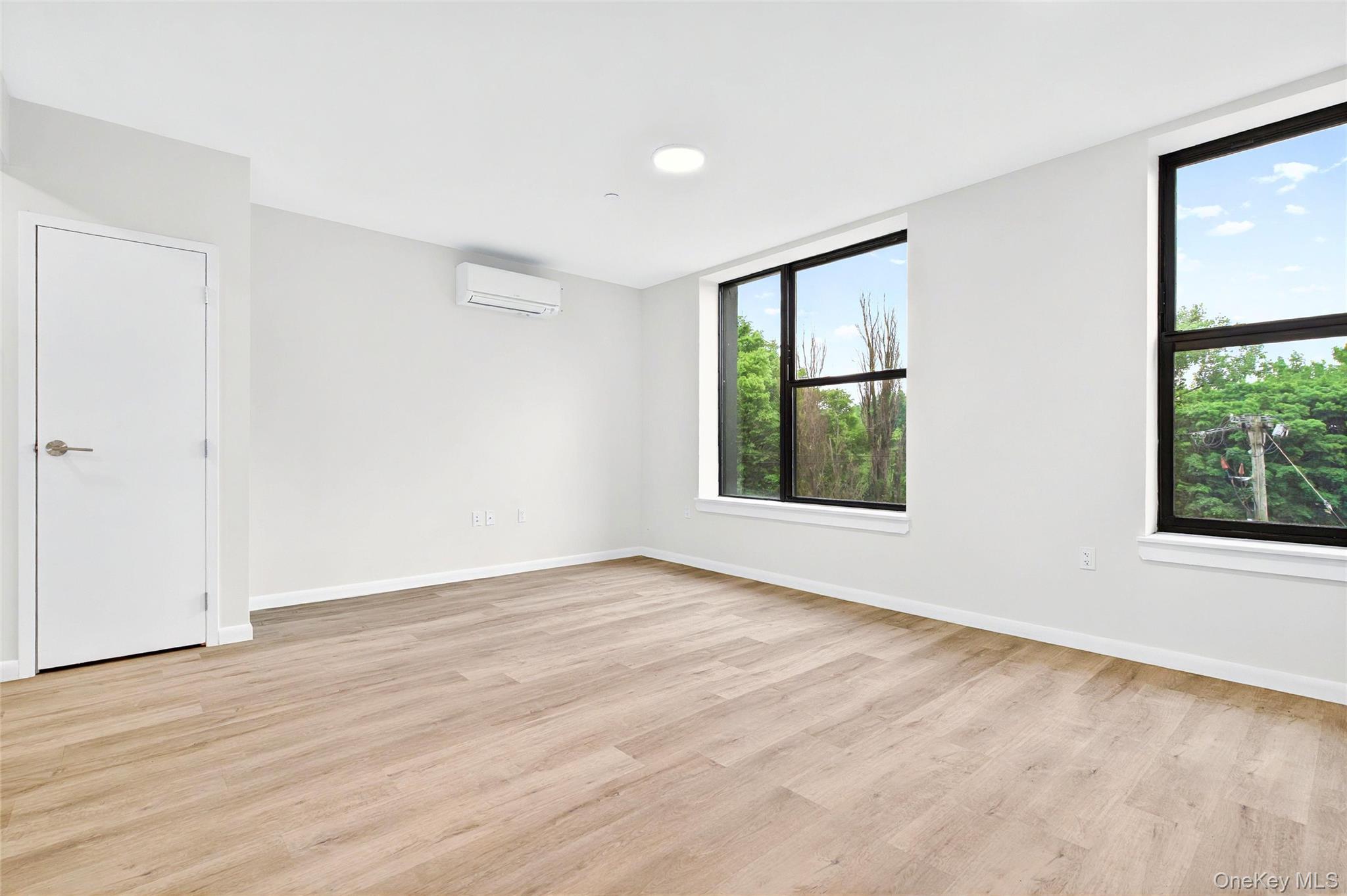 1731 Lacombe Avenue, Unit 4B Bronx, NY 10473 - Photo 11 of 29 Empty room with a wall unit AC, light wood-style floors, and baseboards