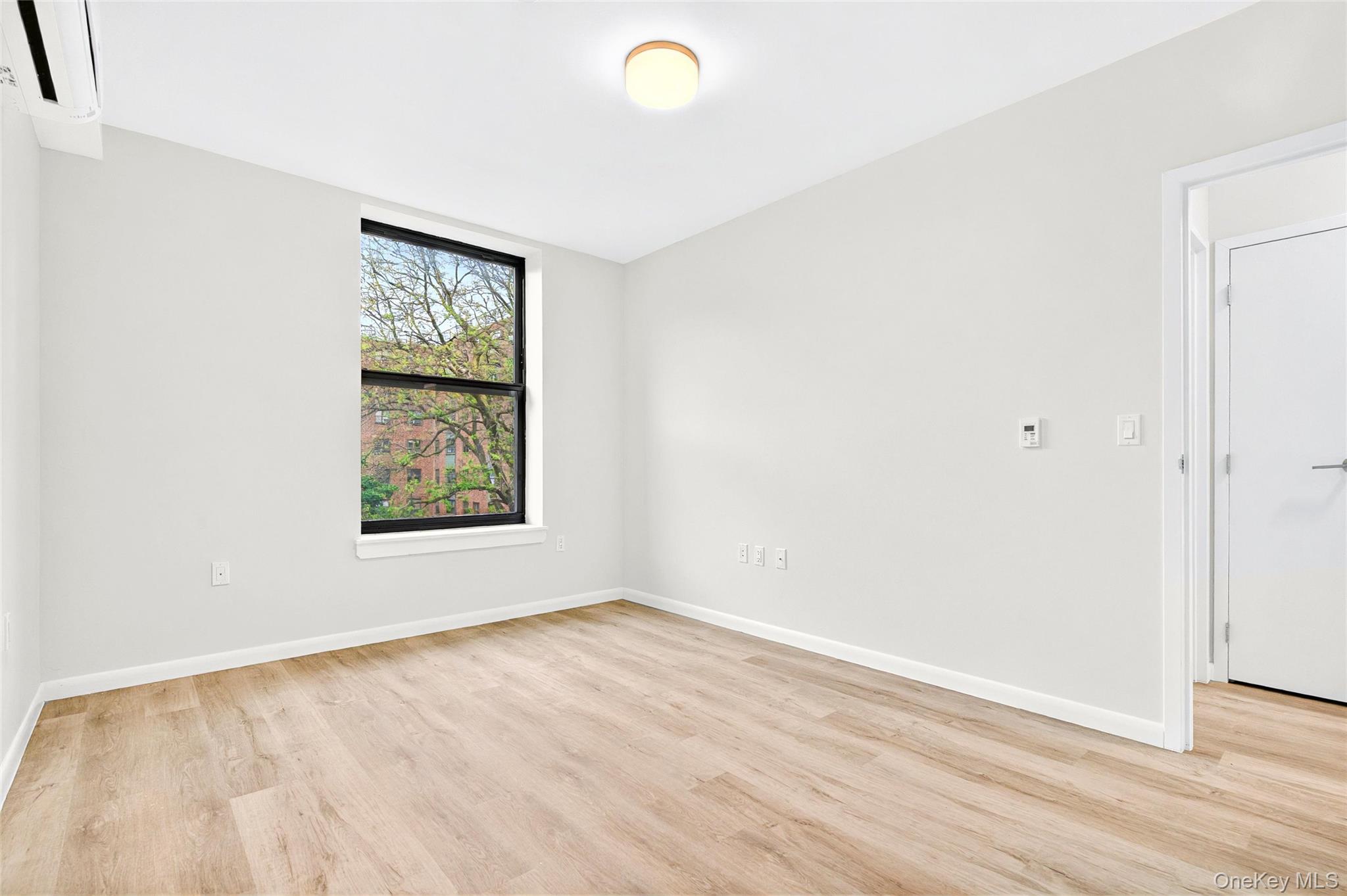 1731 Lacombe Avenue, Unit 4B Bronx, NY 10473 - Photo 21 of 29 Bedroom with an AC wall unit, light wood finished floors, and baseboards