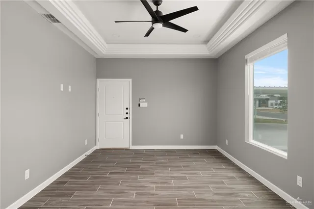 a view of empty room with wooden floor and fan