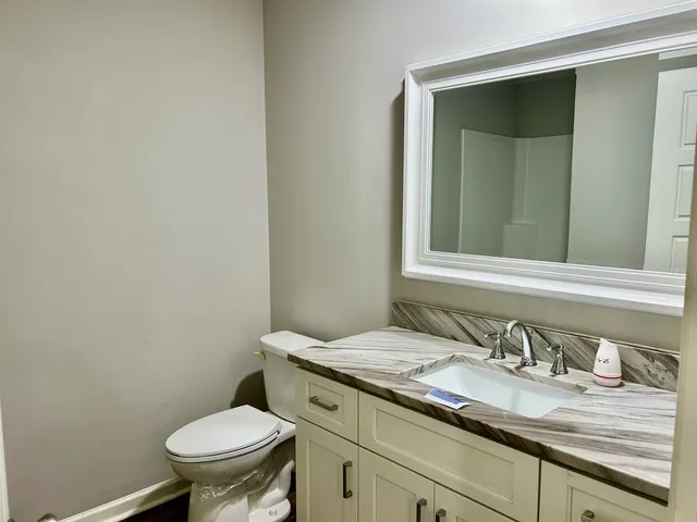 a bathroom with a granite countertop toilet sink and mirror