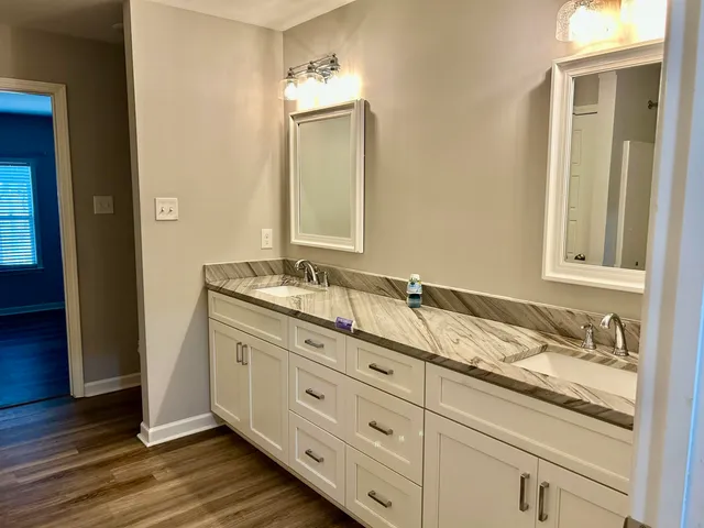 a bathroom with a granite countertop double vanity sink and mirror