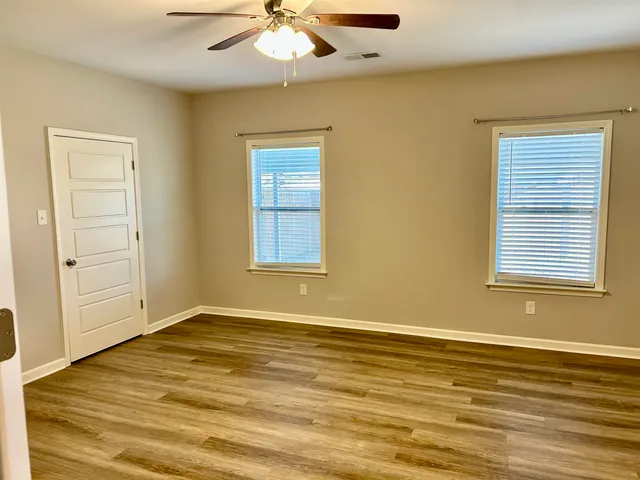 a view of an empty room with window and wooden floor