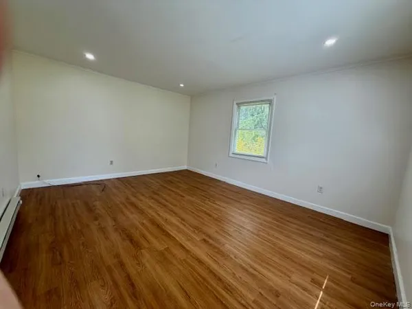 an empty room with wooden floor and window