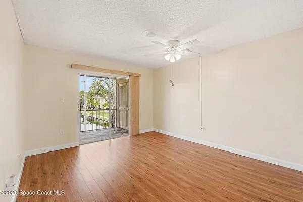 an empty room with wooden floor fan and windows