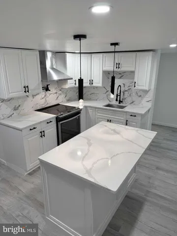 a kitchen with a sink a stove a refrigerator and white cabinets