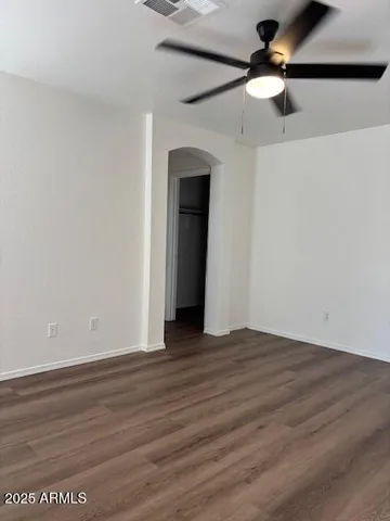 a view of empty room with wooden floor and ceiling fan