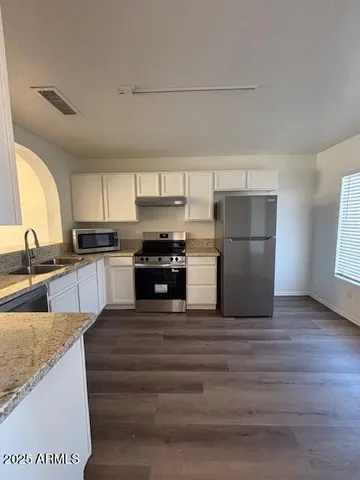 a kitchen with a sink a refrigerator and dishwasher with wooden floor