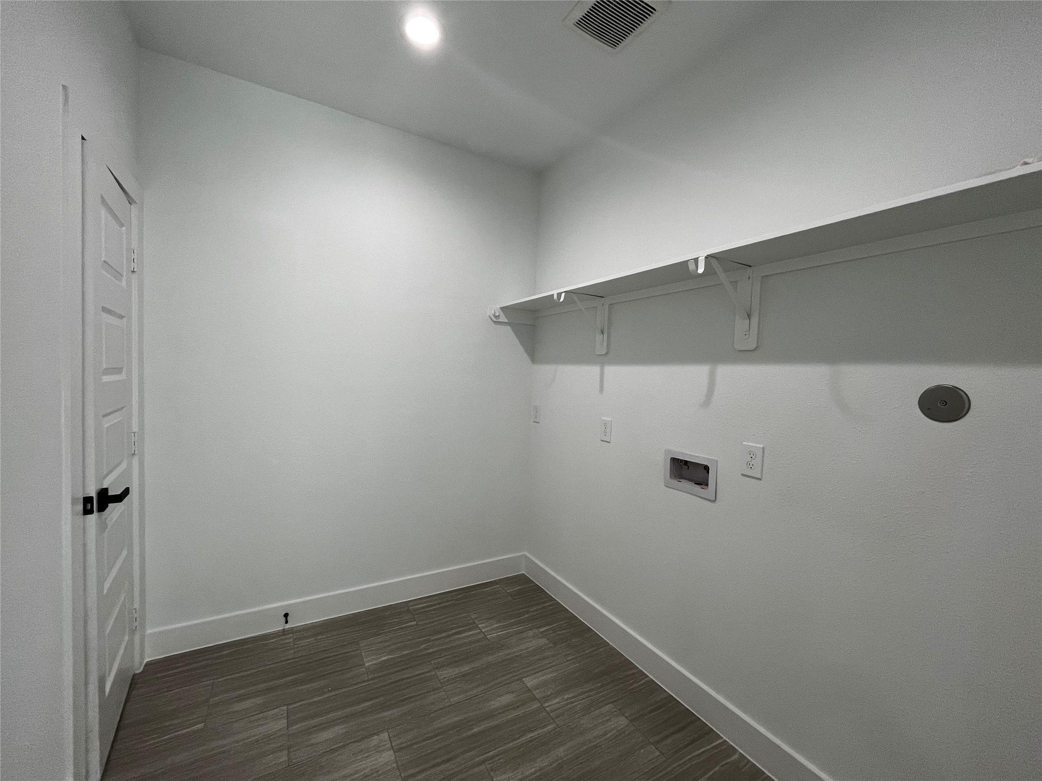 471 Buffalo Trail Angleton, TX 77515 - Photo 28 of 35 This photo shows a small, well-lit laundry room with white walls, a tiled floor, and a shelf. It has connections for a washer and dryer and a door leading to a closet that can be used for storage to the left.