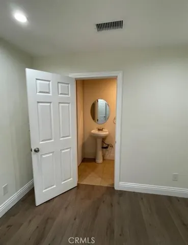an empty room with wooden floor mirror and windows