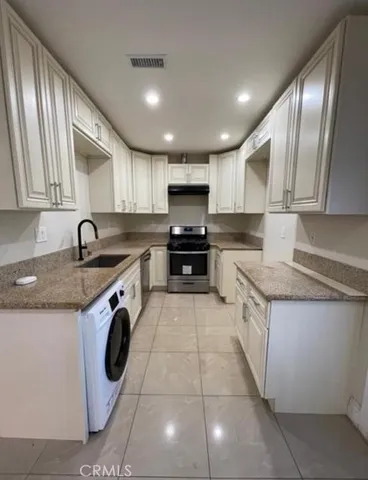 a kitchen with granite countertop a sink a stove top oven and cabinets