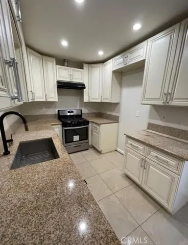 a kitchen with granite countertop a stove sink and cabinets