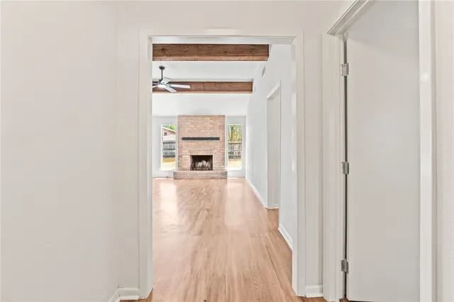a view of a hallway with wooden floor and a kitchen