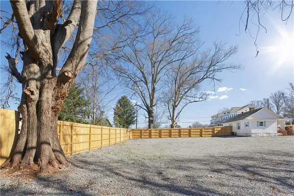 a backyard of a building with trees and a wooden fence