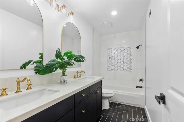 a bathroom with a granite countertop sink a toilet and shower