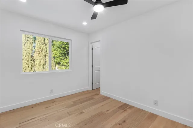 an empty room with wooden floor chandelier fan and windows