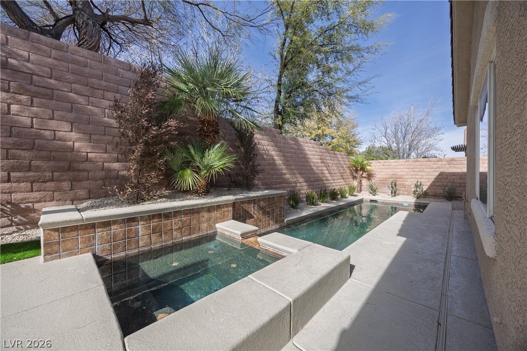 10982 Village Ridge Lane Las Vegas, NV 89135 - Photo 2 of 12 An inviting backyard oasis offers a sparkling in-ground pool with integrated spa and desert-friendly landscaping.