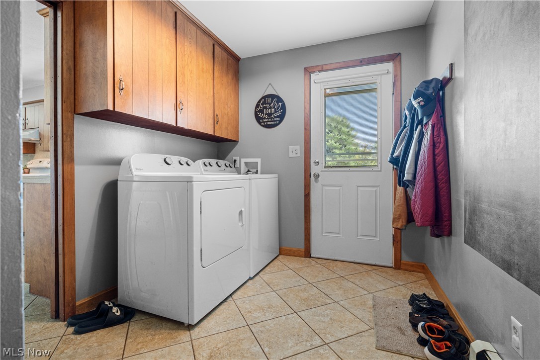 3650 Rambo Avenue Alliance, OH 44601 - Photo 19 of 36 Laundry area featuring tile flooring, wood-finish cabinetry, and an exterior door with integrated window