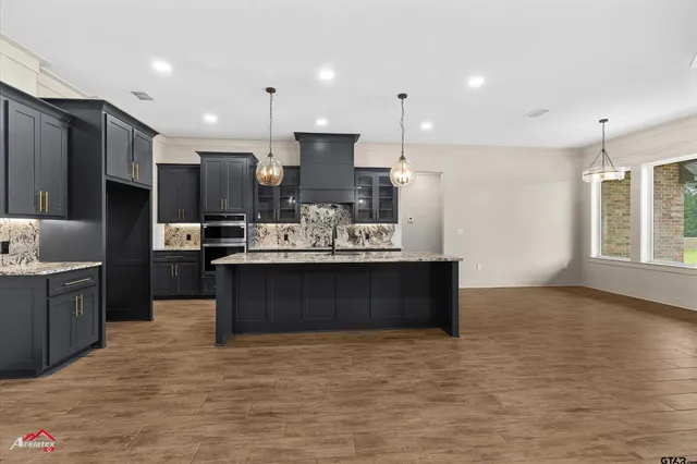 a kitchen with stainless steel appliances kitchen island granite countertop a stove a sink a refrigerator white cabinets a oven and a large window