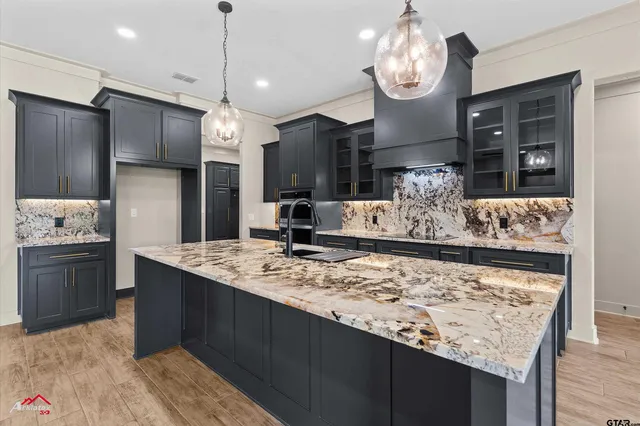 a kitchen with stainless steel appliances granite countertop a sink refrigerator and cabinets