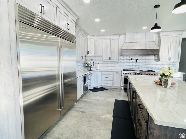 100 Whit Lane Georgetown, ID 83239 - Photo 5 of 76 Kitchen with premium appliances, concrete flooring, light stone counters, a textured ceiling, and hanging light fixtures
