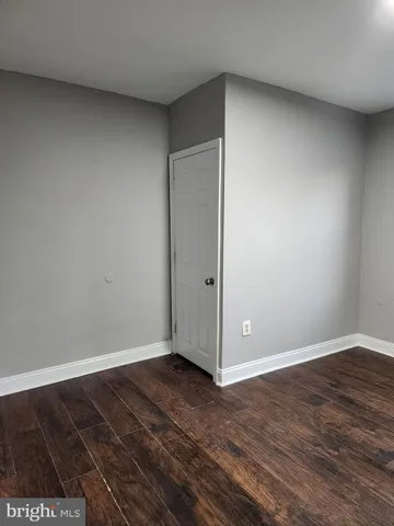 an empty room with wooden floor and fan