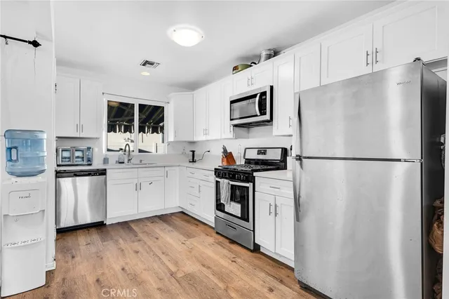 a kitchen with white cabinets white stainless steel appliances and refrigerator