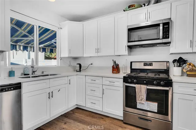 a kitchen with cabinets stainless steel appliances and wooden floor