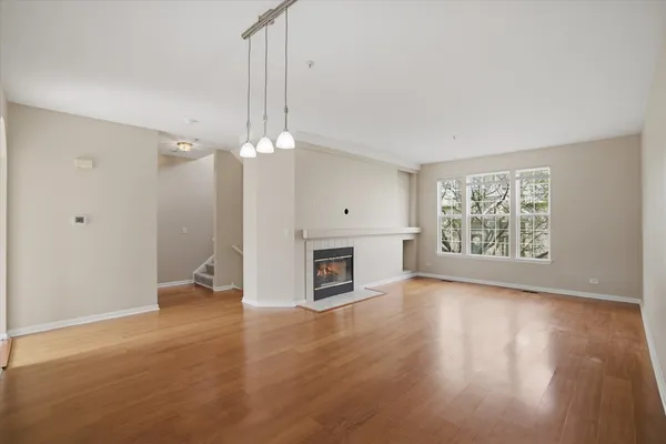 an empty room with wooden floor fireplace and windows