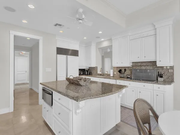 a kitchen with stainless steel appliances granite countertop a kitchen island a stove a sink a refrigerator and white cabinets