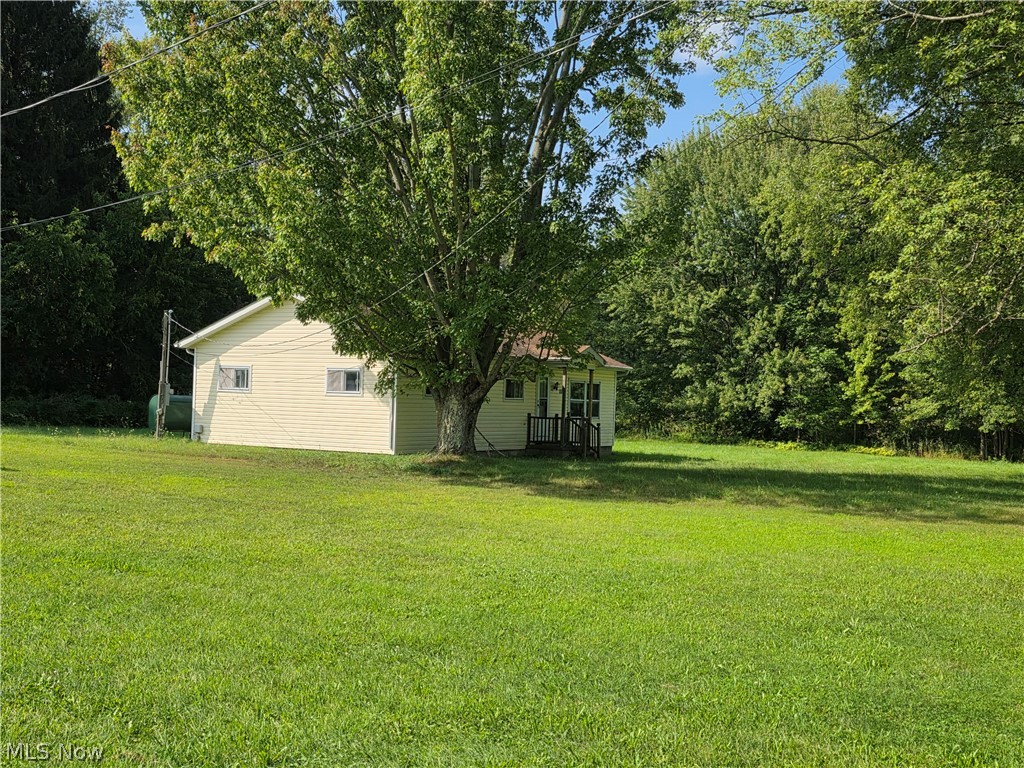 6926 Reed Road Conneaut, OH 44030 - Photo 4 of 11 Expansive green lawn surrounding a light-colored siding structure with a covered entry