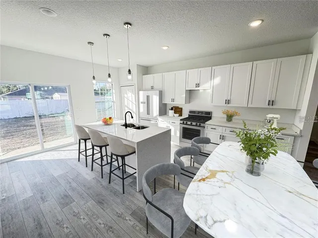 a kitchen with stainless steel appliances kitchen island dining table and chairs