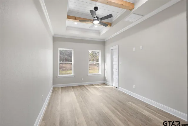 an empty room with wooden floor chandelier fan and windows