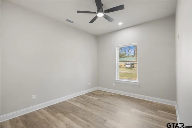 an empty room with a window and a fan