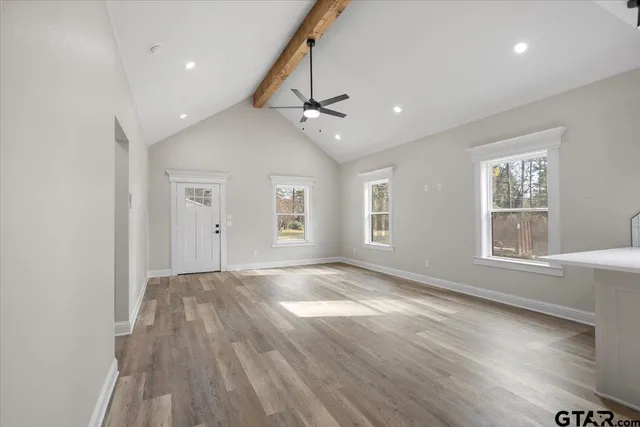 an empty room with wooden floor ceiling fan and windows